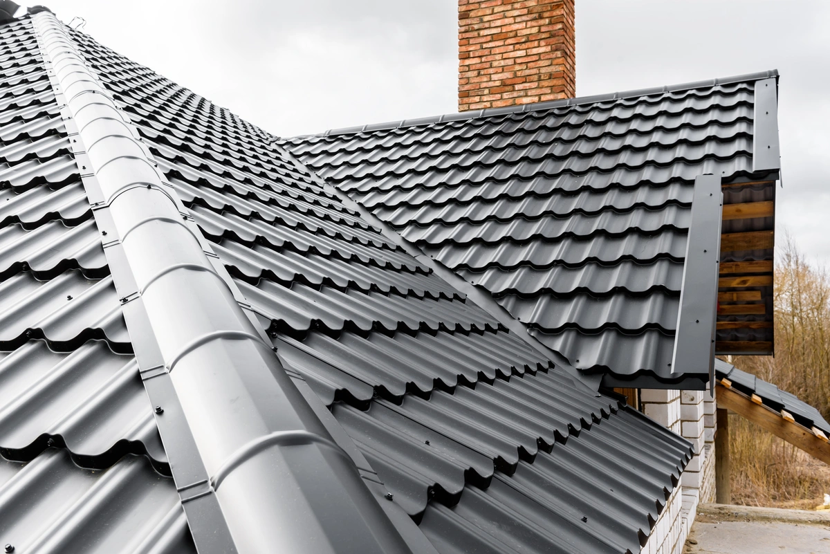 close up of a roof with black metal shingles on a cloudy day