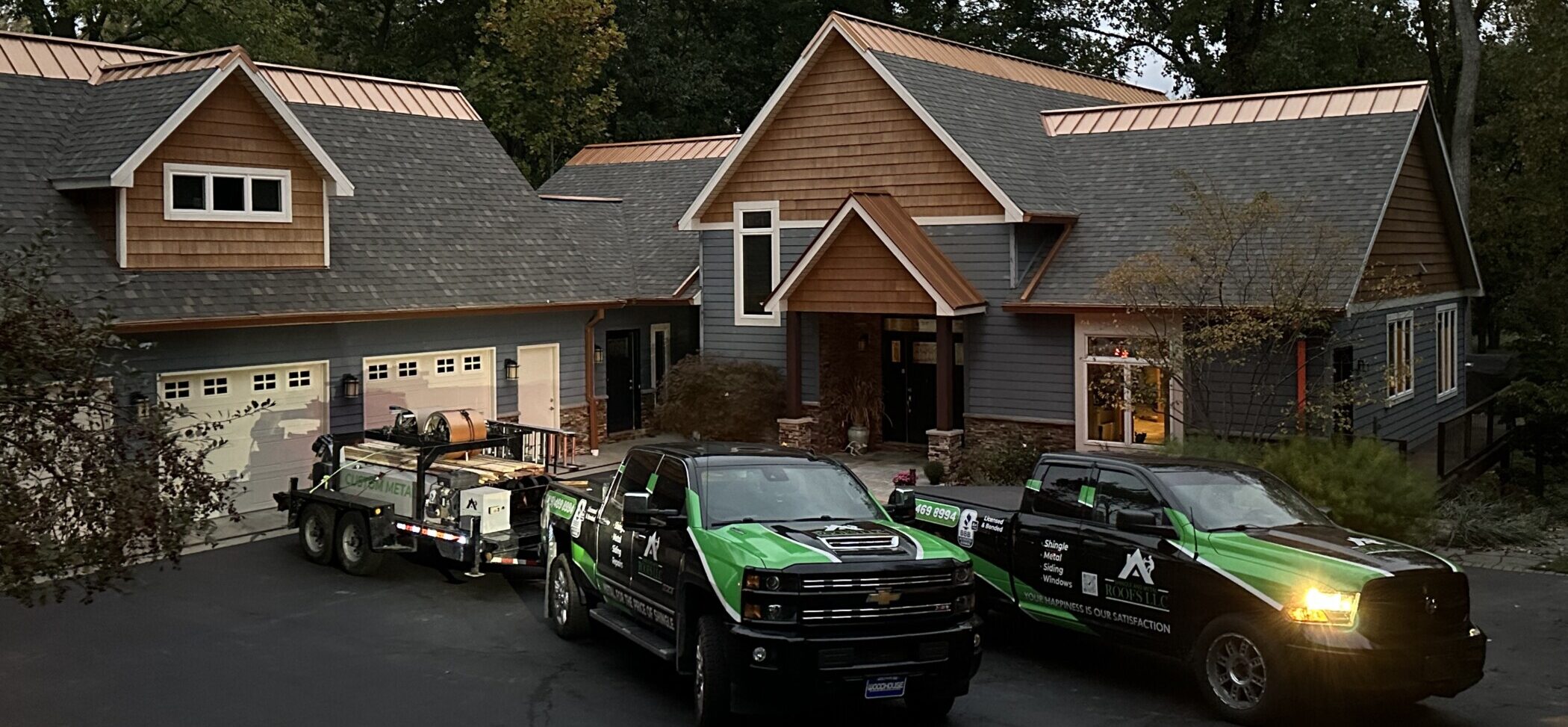 Shingle and Metal Roofs company trucks in front of a recently installed shingle roof with copper ridge cap featuring installation by Shingle and Metal Roofs
