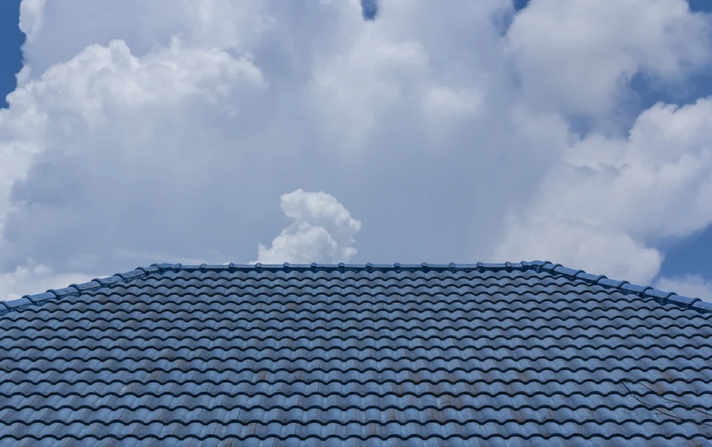 blue tile roof of house against blue sky after roof replacement