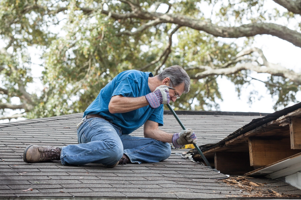 homeowner man repairing his house roof after finding signs of a roof leak