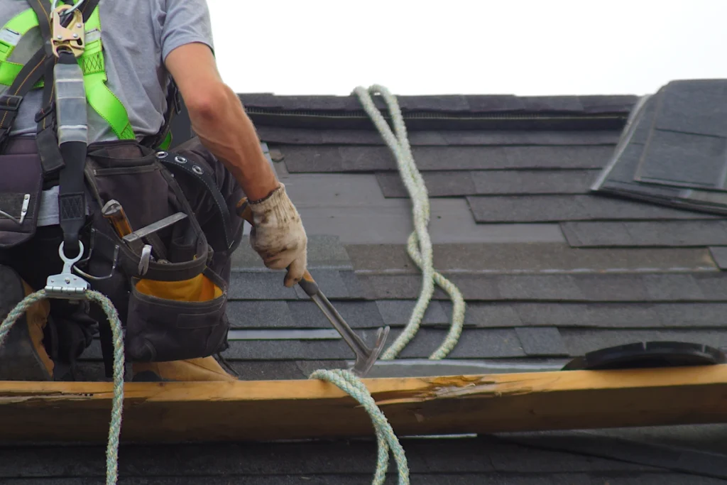 professional roofer removing the granule loss shingles wearing safety gear
