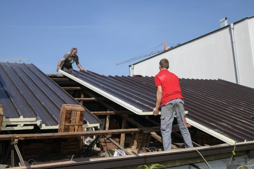 two workers building a roof structure for house