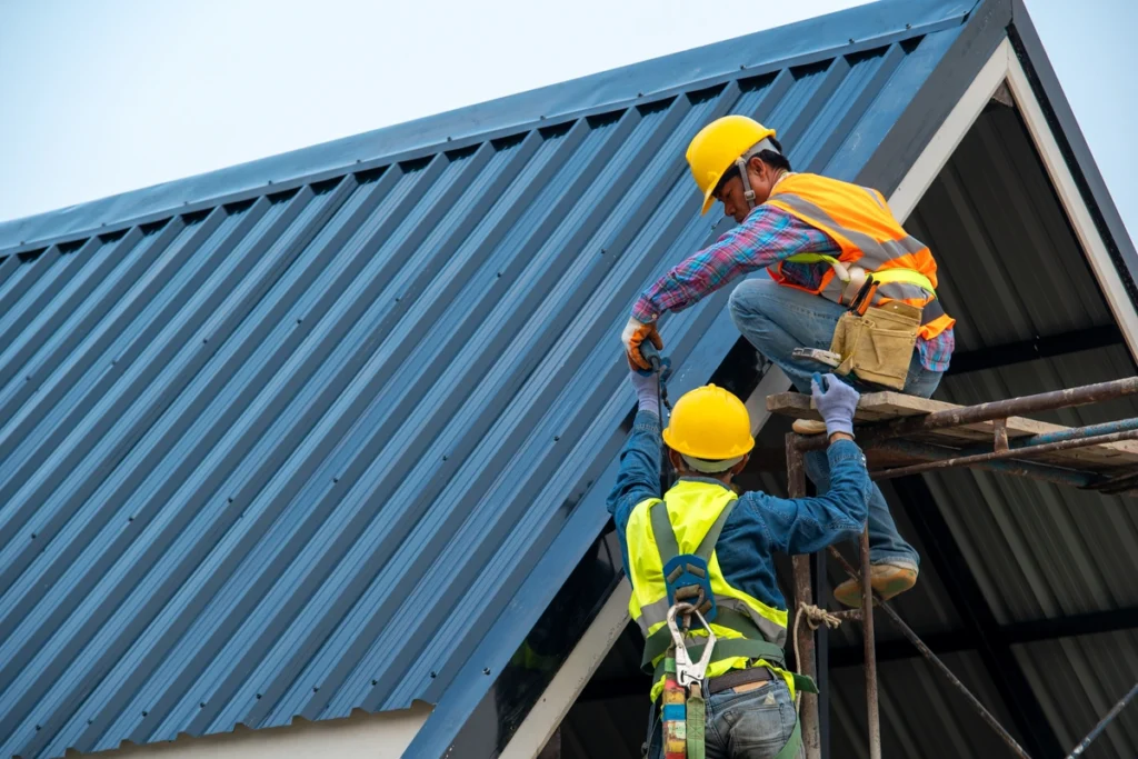 roofing professionals installing metal roof wearing safety belt and helmet