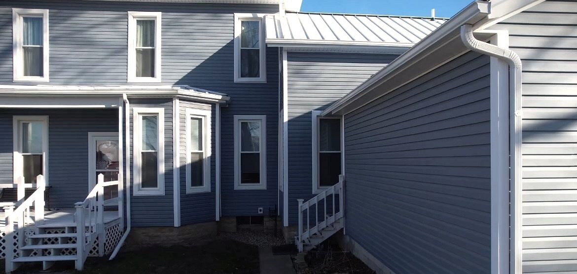 Custom windows paired with blue Polaris vinyl siding installed by Shingle and Metal Roofs LLC