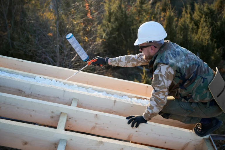 man using spray foam insulation on roof