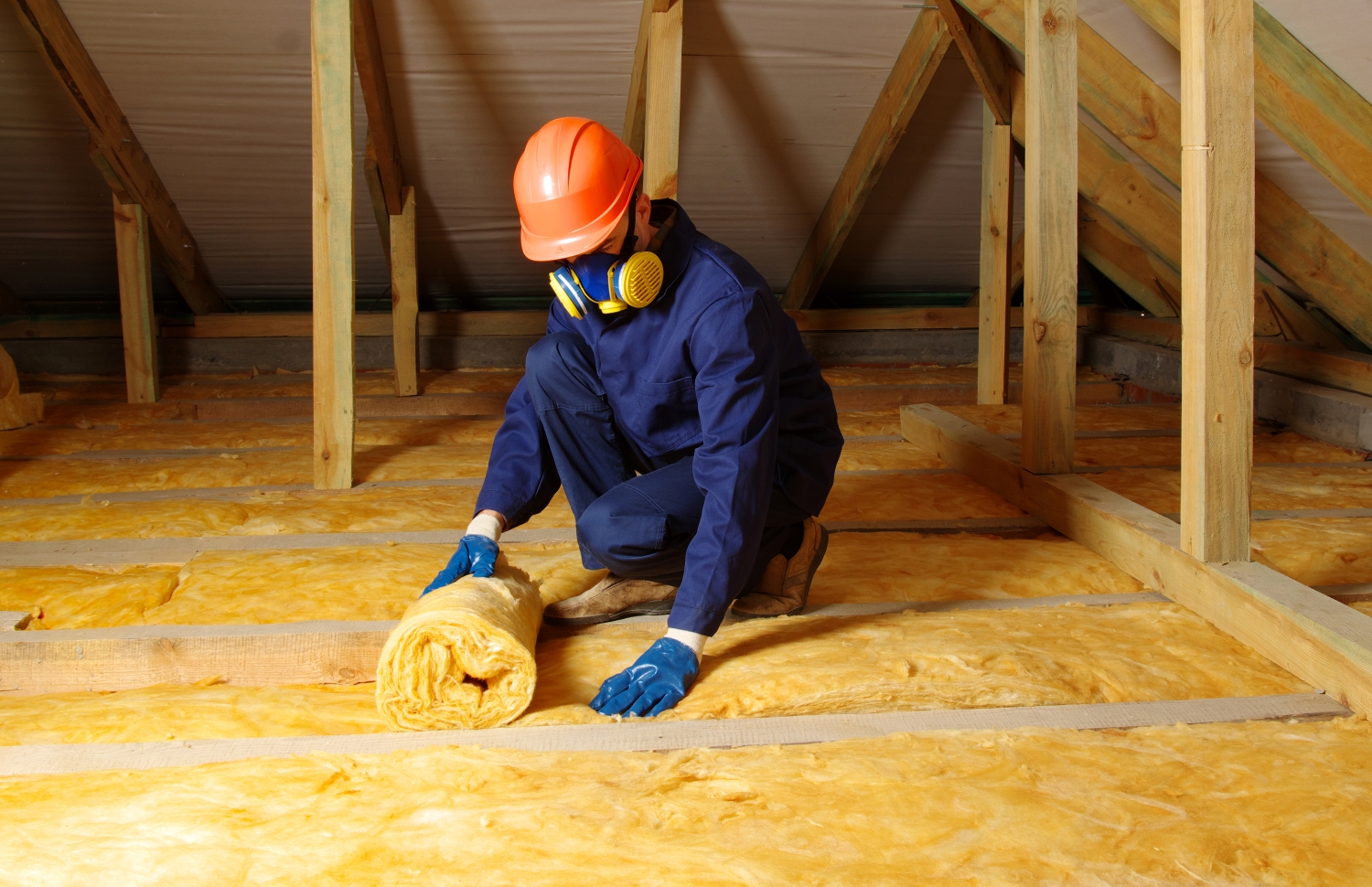 A worker installing insulation in the attic, ensuring proper thermal protection and energy efficiency for the home.