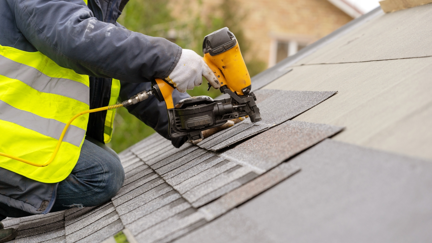 A man drilling into the shingles, likely for installation or repair purposes.