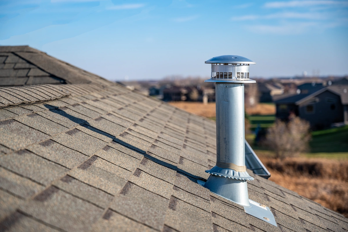 roof boot-side angle of metal piping coming from gray shingled roof